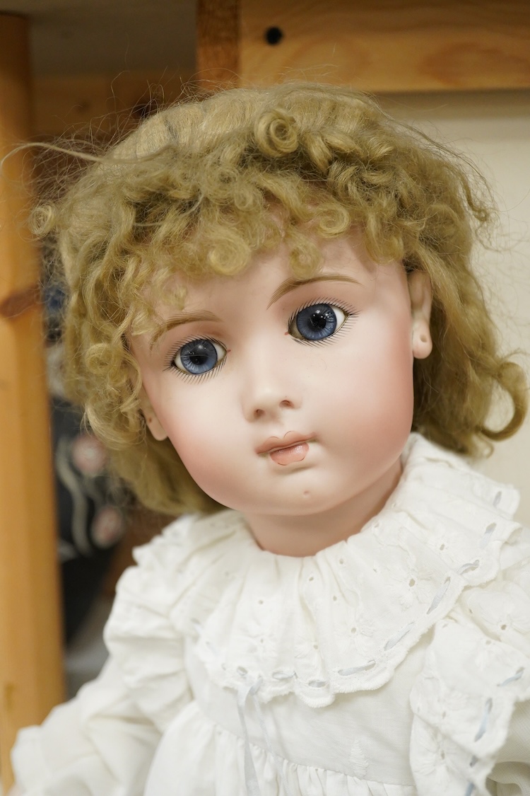 A large jointed bisque head doll and two miniature bisque dolls